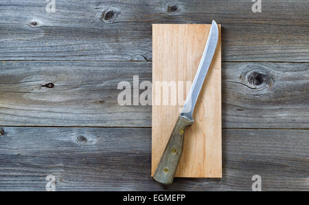 Top view angled shot of a vintage single large knife on cutting board with rustic wooden boards underneath. Stock Photo