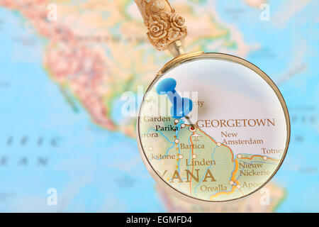 Blue tack on map with magnifying glass looking in on Georgetown, Guyana Stock Photo