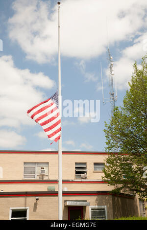 American flag flies at half- staff next to a fire station in North Adams Massachusetts. Stock Photo
