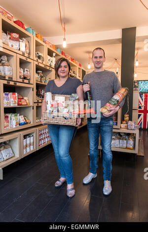 shop keepers / small business owners stand in the interior of gourmet luxury food and drink shop proudly displaying their wares Stock Photo
