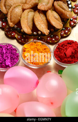Gujia is a cuisine of India surrounded by colorful gulaal in the bowls & balloons. Stock Photo