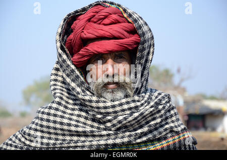 Indian village elder wearing a red turban and black and white scarf Kalpi Village Rajasthan India Stock Photo