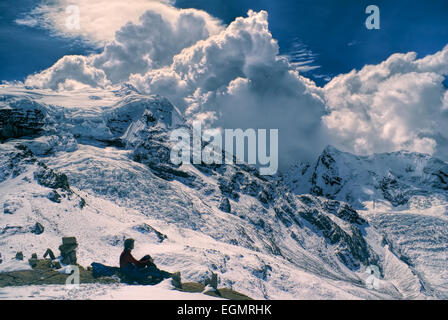 Young hiker sitting in south american Andes in Peru, Ausangate with dramatic clouds forming above the mountains Stock Photo