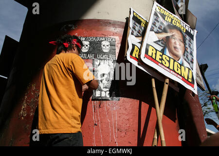 Manila, Philippines. 27th February, 2015. A protester pasting posters caalling to junk the Enhanced Defense Cooperation Agreement between the Philippines and the U.S. during the protest rally in Mendiola, Manila. Composed mostly of students, they walked out of their class to air their resentment over Aquino's alleged inefficiency in governing and solving the country's problems. Militant groups also joined the march to the call for Aquino's resignation. Credit:  J Gerard Seguia/Pacific Press/Alamy Live News Stock Photo