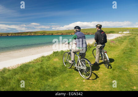 Young man and woman resting on their bicycles while cycling on South Ronaldsay, Orkney Islands, Scotland. Stock Photo