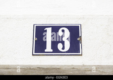 Number thirteen on a wall in a house, detail of a wall with a figure on a plate Stock Photo