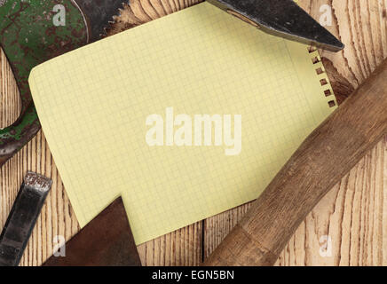 Old carpentry tools and a piece of notebook on a wooden background Stock Photo