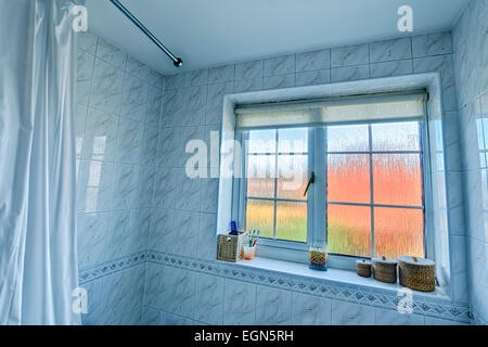 Wide angle bathroom interior, inc edge of shower curtain and curtain rail, tiled walls, frosted glass window. Stock Photo