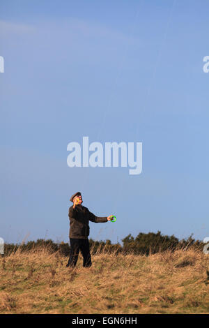 Older man flying stunt kite using dual control lines against blue sky Stock Photo