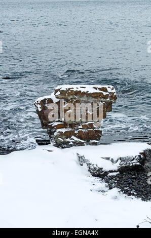 Pulpit Rock, a snow-covered sea stack off the Shore Path in Bar Harbor, Maine.