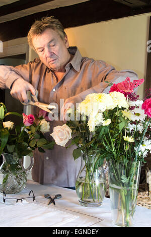 Senior man arranging cut flowers in vases Stock Photo