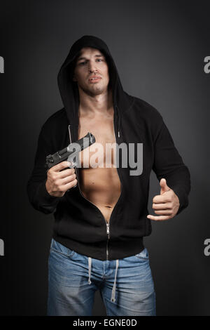 male gangster holding a gun isolated on gray background Stock Photo