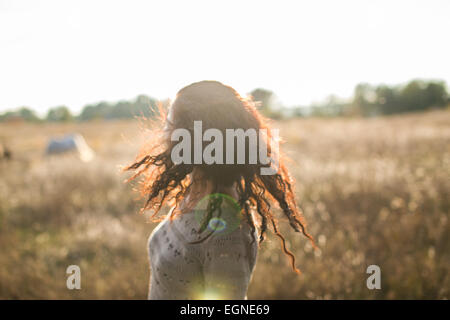 Young girl shaking her head on a walk in the field at sunset Stock Photo