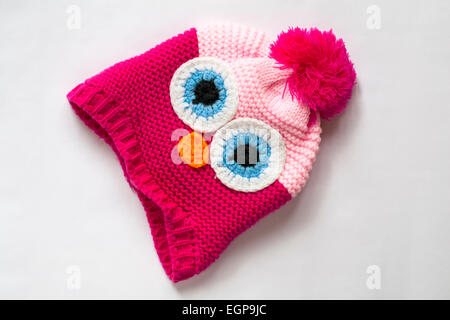 pink face knitted hat with pompom isolated on red background Stock Photo
