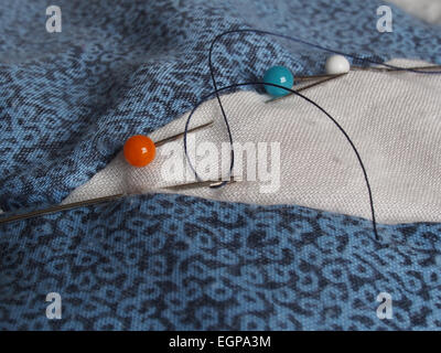 Pins and a threaded sewing needle involved in patchwork Stock Photo