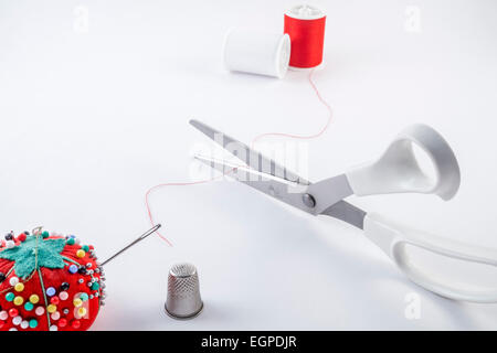 Spools of thread with sewing pins needle scissors and thimble on white background Stock Photo