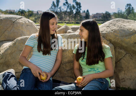 Two nature natural Tween tweens 11-12-13 year old olds Vietnamese-Caucasian Hispanic Mexican girls talking share fruit looking young person people Myrleen Pearson Stock Photo