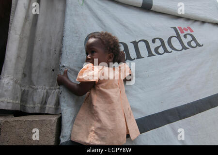 A young girl stands next to a tent donated by Canada at a makeshift camp for survivors of a 7.0 magnitude earthquake which struck Haiti on 12 January 2010 in Port-au-Prince Stock Photo