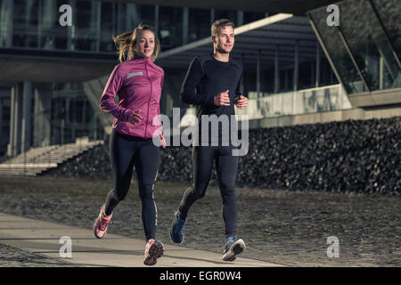 Active young couple jogging side by side in an urban street during their daily workout in a health and fitness concept Stock Photo