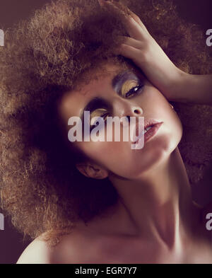 Dreamy Woman with Frizzy Hairstyle and Golden Eyeshadow Stock Photo