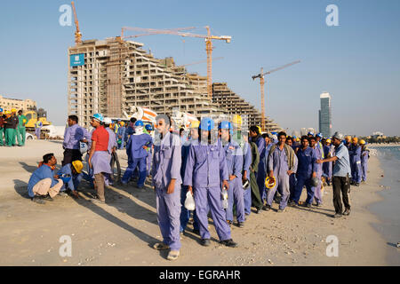 Construction workers queuing to get on bus to living quarters at end of working day in Dubai United Arab Emirates Stock Photo