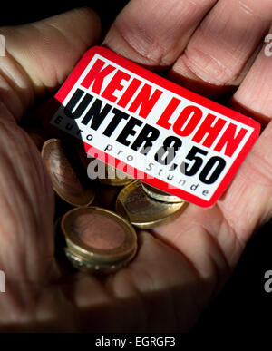 Dresden, Germany. 26th Feb, 2015. ILLUSTRATION - A man holds euro coins, worth 8, 50 euro, and a sticker, issued by the Confederation of German Trade Unions (DGB), which reads 'No wages below 8, 50 euro per hour', in his hands in Dresden, Germany, 26 February 2015. Photo: Arno Burgi/dpa/Alamy Live News Stock Photo