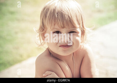 Outdoor close-up portrait of funny smiling Caucasian blond baby girl. Vintage toned photo with retro toning filter effect Stock Photo