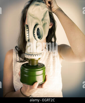Woman holding gas mask in front of her face Stock Photo