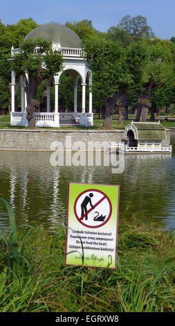 A gazebo by a pond in Kadriorg Park Tallinn Estonia with a sign  in multiple languages to prohibit feeding the swans Stock Photo