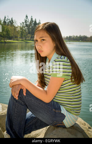 Biracial girl with long dark hair smiles in a floral dress. She stands ...