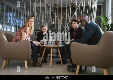 Portrait of multiethnic business team sitting in office lobby looking at camera smiling. Successful business team together. Stock Photo