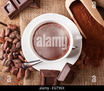 Cup of hot chocolate with cocoa powder, cocoa beans and pieces of chocolate. Stock Photo