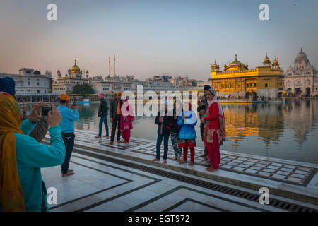 A Sikh family gather for a photograph in front of the The Golden Temple, Amritsar at dusk. Stock Photo