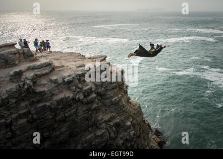 The Diving Monk at the El Salto del Fraile Restaurant in Lima Peru dives off a cliff as tourists watch Stock Photo