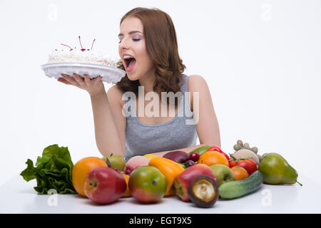 Portrait of a beautiful woman bitting cake over gray background Stock Photo