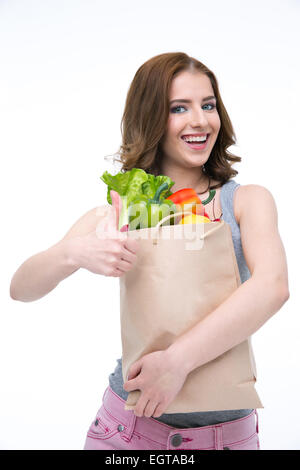 Happy woman holding a shopping bag full of groceries and showing thumb up Stock Photo