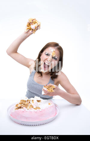 Angry young woman wants to throw cake into the camera Stock Photo