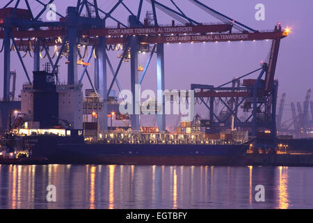 Containererschip is charged at dusk, at Container Terminal Altenwerder, Hamburg harbor, Germany Stock Photo