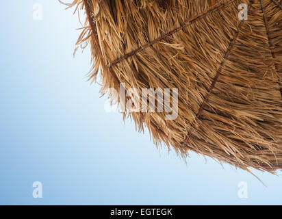 Thatched umbrella viewed from below with blue sky. Stock Photo
