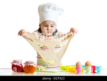 Little girl in cap of the cook playing with dough Stock Photo
