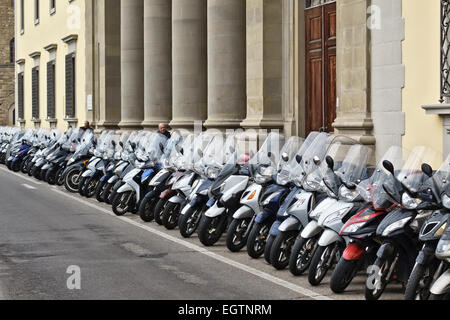 A long row of neatly parked motorcycles, mopeds and scooters in Florence, Italy Stock Photo