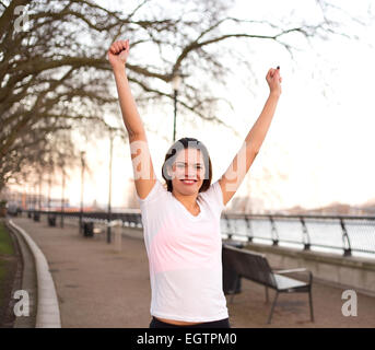 young woman outdoors celebrating a fitness goal Stock Photo
