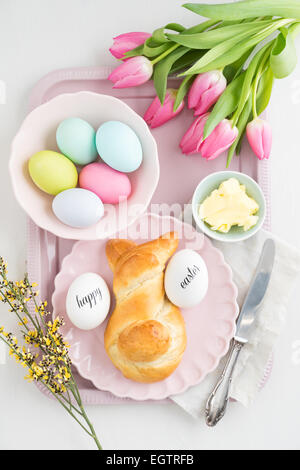 Easter breakfast table with Easter eggs, tulips and sweet yeast Easter bunny bread Stock Photo