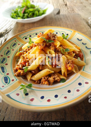 Fresh cooked pene and bolognese ragout served on a plate in a table setting. Serving suggestion Stock Photo