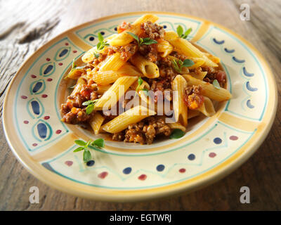 Fresh cooked pene and bolognese ragout served on a plate in a table setting. Serving suggestion Stock Photo