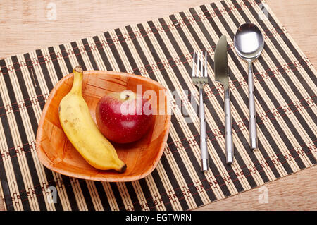 Bowl with banana and strawberry and cutlery on the table Stock Photo