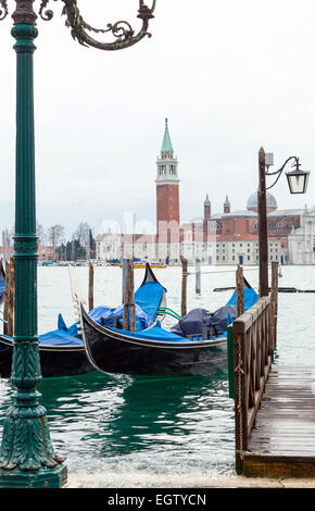 typical Venetian gondolas with high tide that causes the famous event of high water in Venice, Italy. Stock Photo