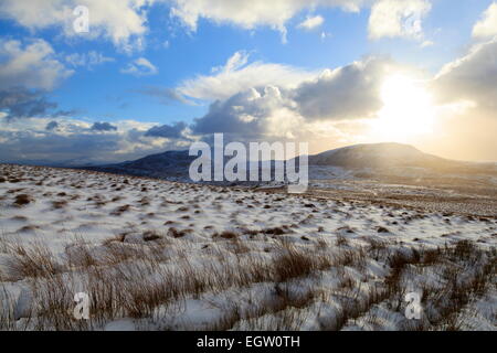 A low Winter Sun begins to set over Arenig Fach, Snowdonia. Arenig Fawr can be seen to the Left Stock Photo