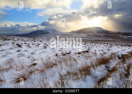 A low Winter Sun begins to set over Arenig Fach, Snowdonia. Arenig Fawr can be seen to the Left Stock Photo