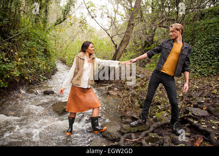 Woman helping man across creek. Stock Photo
